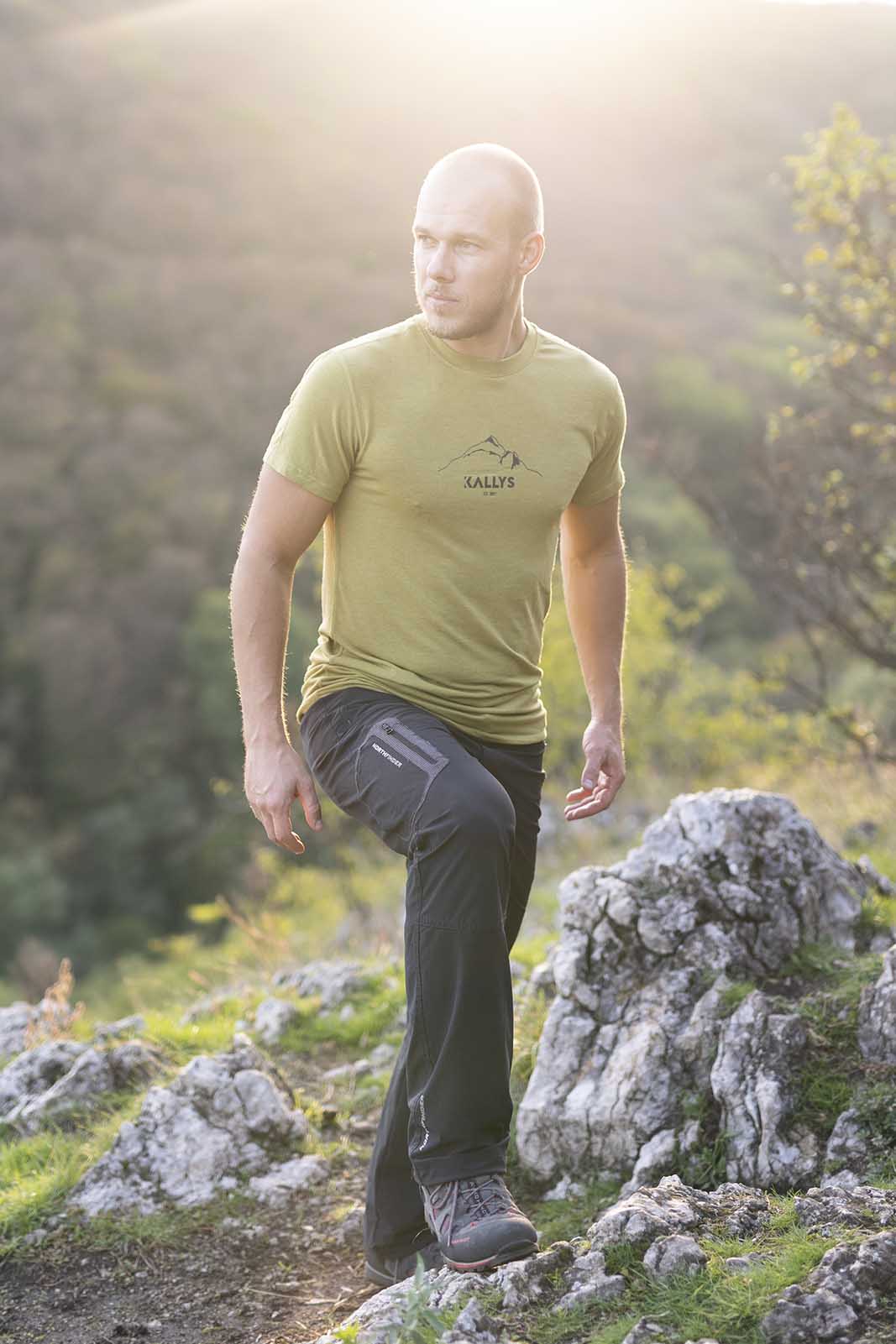 Ein Mann steht aufm Berg. Hat ein kurzarm Tshirt aus Merino der Marke KALLYS an.