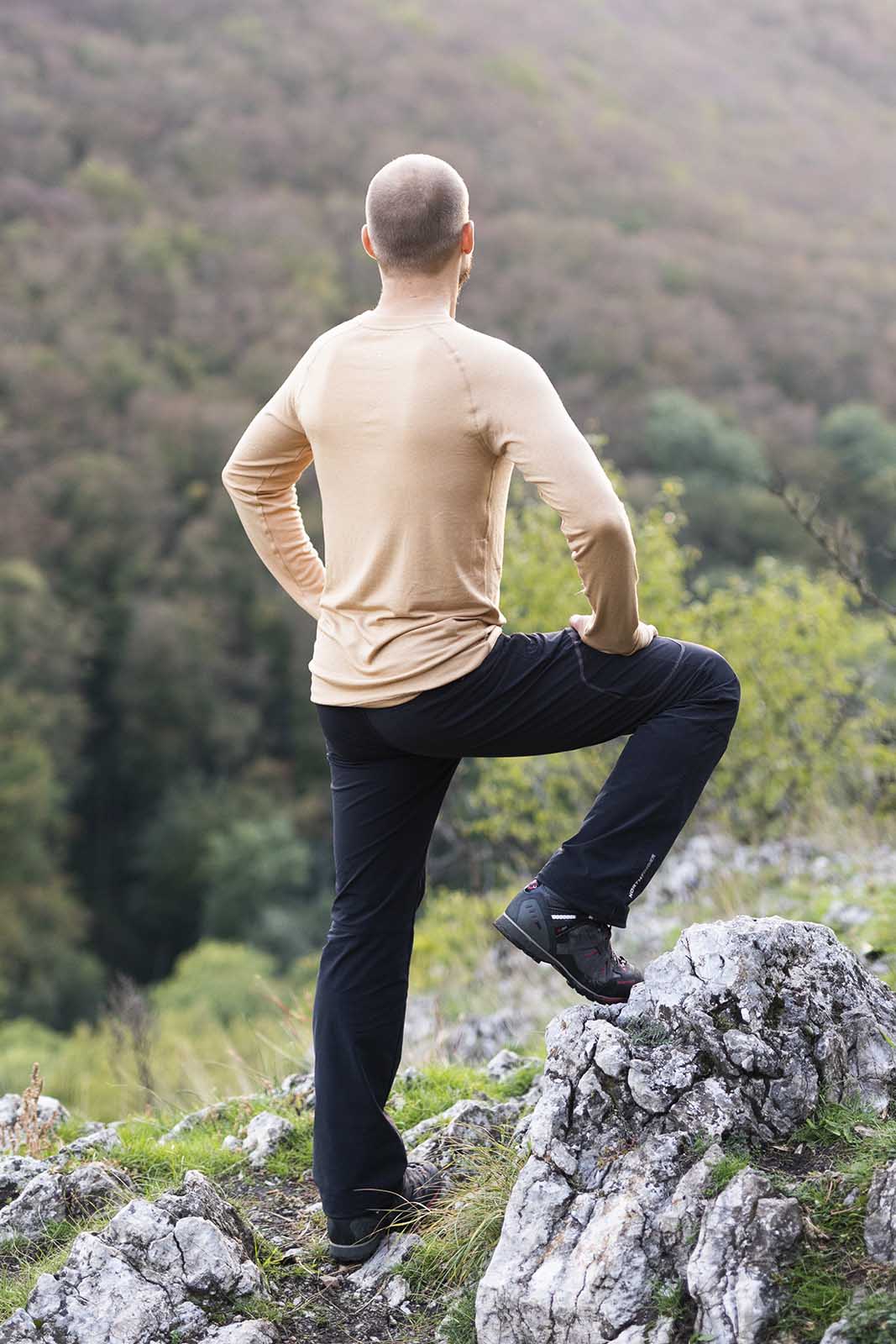 Ein Mann steht aufm Berg. Hat ein langarm Tshirt aus Merino der Marke KALLYS an.