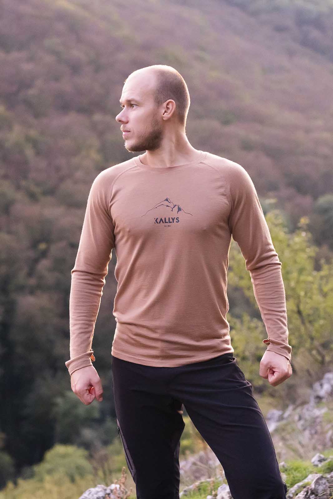 Ein Mann steht aufm Berg. Hat ein langarm Tshirt aus Merino der Marke KALLYS an.