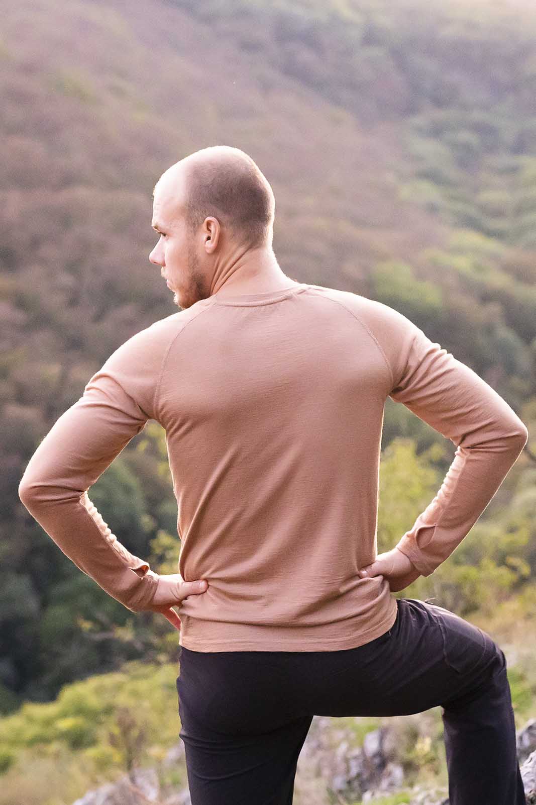 Ein Mann steht aufm Berg. Hat ein langarm Tshirt aus Merino der Marke KALLYS an.