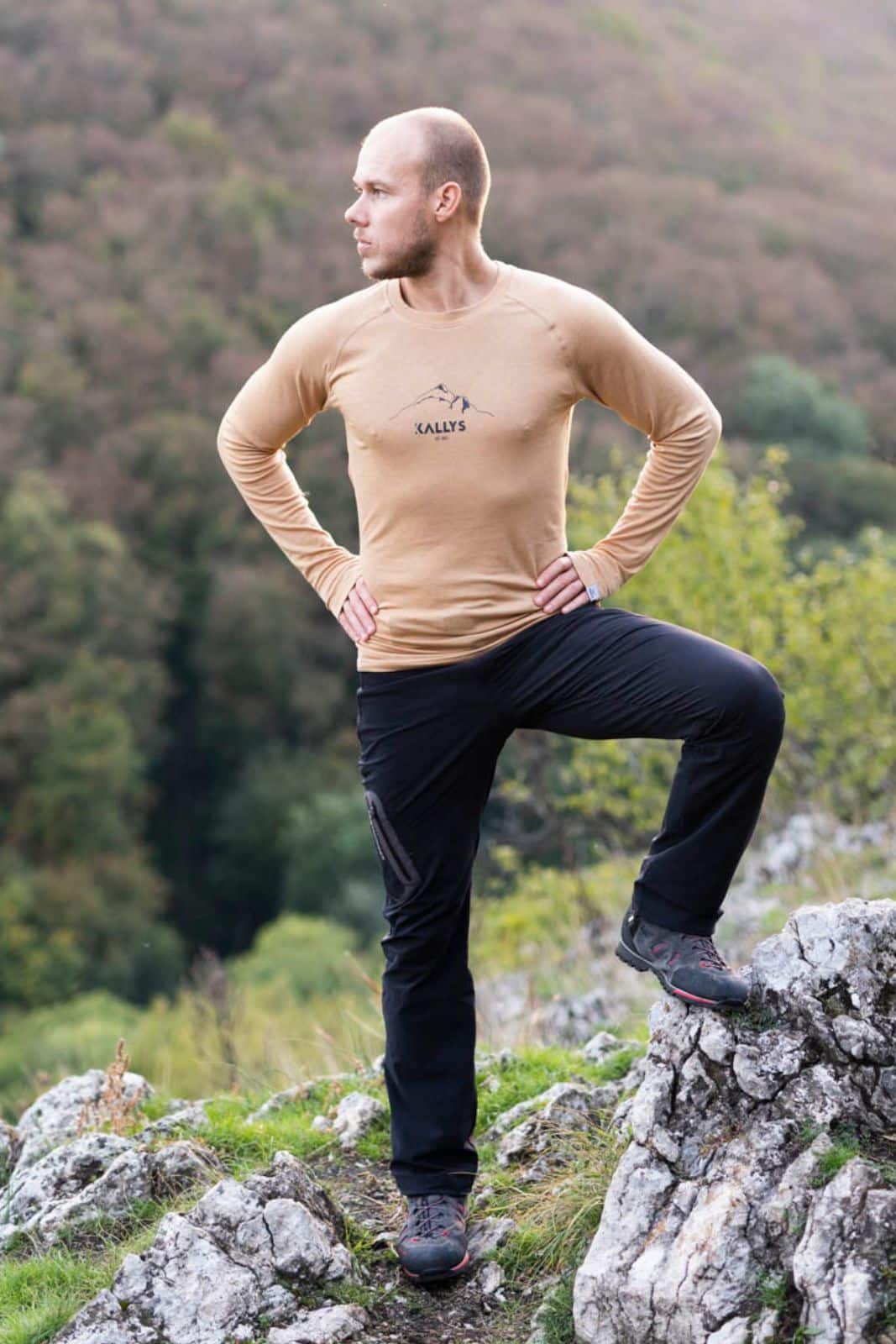 Ein Mann steht aufm Berg. Hat ein langarm Tshirt aus Merino der Marke KALLYS an.